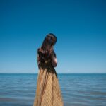a woman standing in the water looking at the ocean